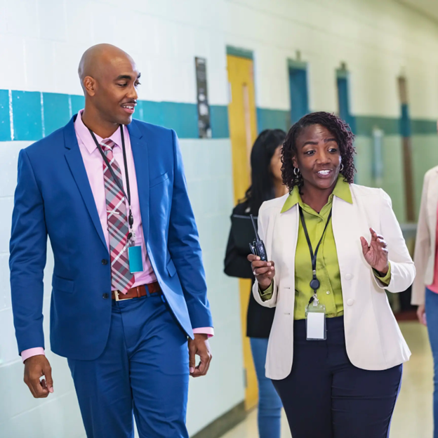 Two leaders walking down a school hallway while talking