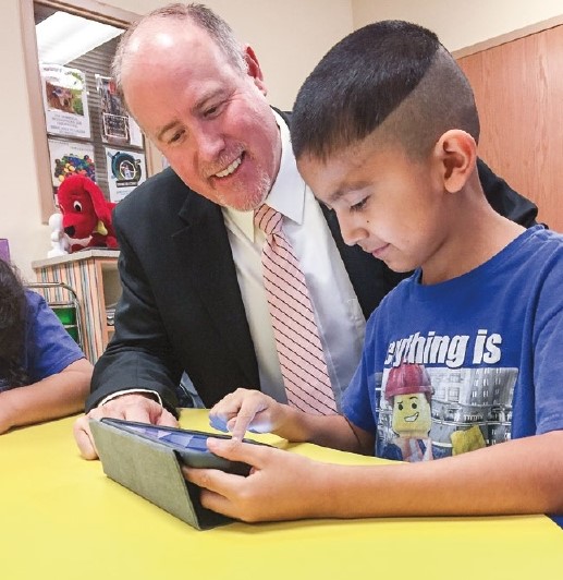 Jeff Dillon helping young student working with a tablet